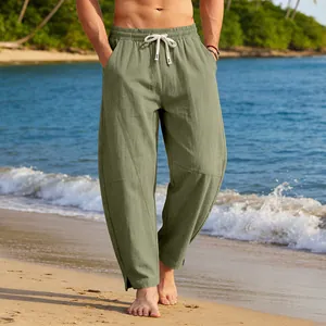Détail d'un pantalon ample en coton vert pour homme avec ourlet fendu sur la plage.