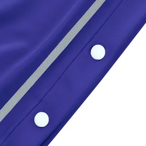Gros plan des boutons-pression blancs et de la bande grise sur le pantalon de basket bleu