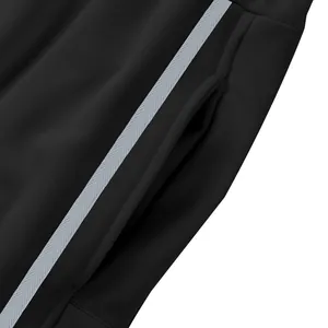 Gros plan sur la poche latérale et la rayure grise d'un pantalon de sport noir épais