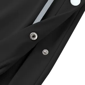 Détail macro de boutons-pression en métal argenté sur un pantalon de basket-ball noir lourd.