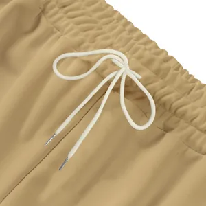 Gros plan sur la taille élastique d'un jogging kaki avec cordons blancs et embouts métal
