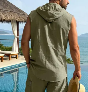 Men's olive green linen hooded sleeveless shirt and cargo shorts in beach resort scene.