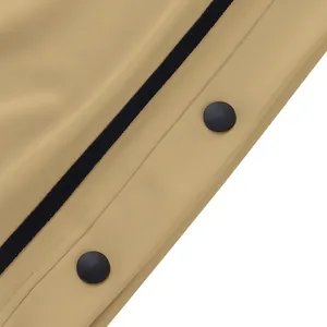 Gros plan sur les boutons-pression noirs et les bandes des pantalons kaki.