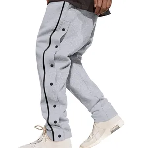 Détail du pantalon de jogging gris pour hommes avec rayures noires et boutons-pression.