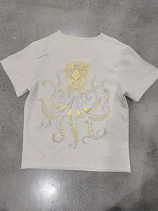 Vista dettagliata della stampa a foglia di polpo dorata su t-shirt grigia in lino fiammato.
