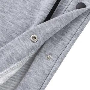 Vue détaillée des boutons-pression en métal et du tissu gris chiné de ce pantalon de sport.