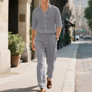 Detailed view of a man wearing a grey linen-blend long sleeve shirt and matching trousers