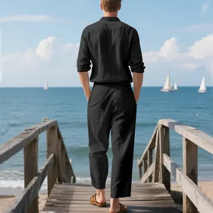 Back view of a man in black linen long sleeve shirt and trousers on a seaside wooden pier