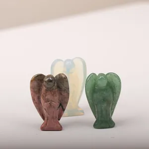 Detailed view of three carved crystal angels in pink, white, and green gemstones