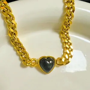 Detail of thick gold cuban chain bracelet with a black heart-shaped zircon pendant