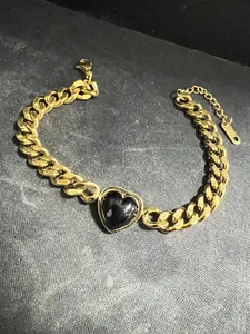 Detailed macro shot of 18K gold plated Cuban link bracelet featuring a black heart charm.
