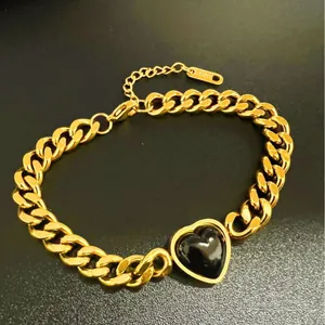 High-quality close-up of a gold-plated titanium steel bracelet with a black heart charm