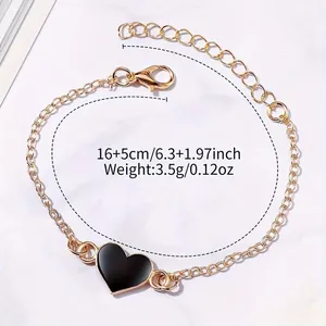 Detailed view of a gold chain bracelet with black heart charm and measurements