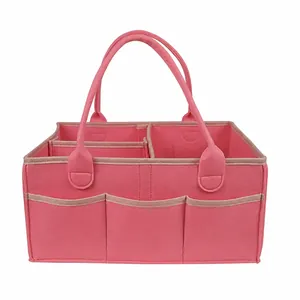 Vista detallada de una bolsa organizadora de pañales de fieltro rosa con compartimentos