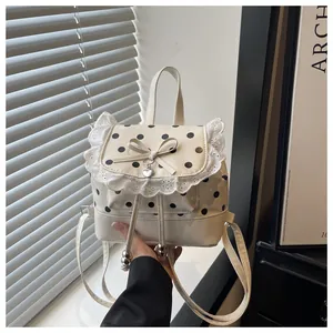 Primo piano di un piccolo zaino a pois crema con pizzo bianco e adorabile fiocco decorativo