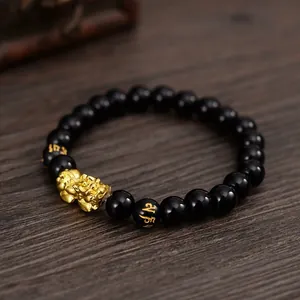 Close-up of black obsidian style bracelet with golden Pi Xiu and Six True Words mantra