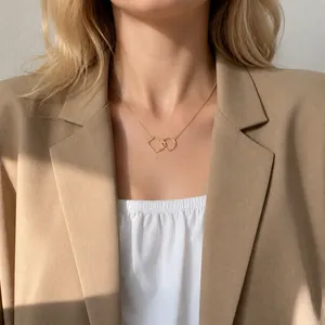 Gros plan d'un collier minimaliste en or à anneaux entrelacés porté par un mannequin
