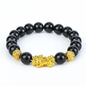 Close-up view of the black obsidian beads and golden Pixiu charm on a spiritual bracelet.
