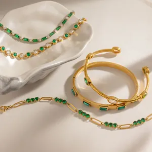 Detalle de pulseras chapadas en oro con circonitas verde esmeralda en acero inoxidable.