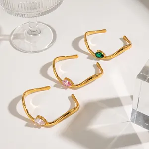 Three elegant wavy gold bangles with teardrop-shaped emerald, pink, and clear zircons.