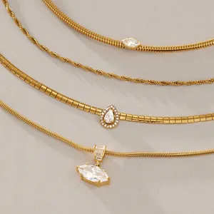 Detail view of stacked gold titanium steel necklaces with sparkling crystal pendants