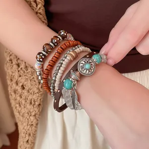 Detailopname van Boheemse kralenarmbanden met turquoise en veerhangers om de pols.