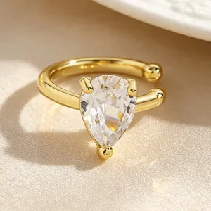 Close-up detail of a gold-tone ear cuff featuring a sparkling pear-shaped zircon gemstone.