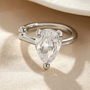 Macro detail of a silver-tone twisted ear cuff with a clear pear-cut zircon stone.