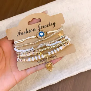 Vintage ethnic beaded bracelet set with Evil Eye and Hamsa charms on kraft card display.