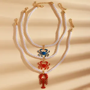 Detail of colorful lobster and crab pendants on white twisted rope necklaces for beach style.
