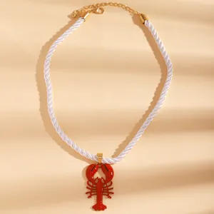 Detail of beach style necklace with vibrant red lobster pendant and white rope cord