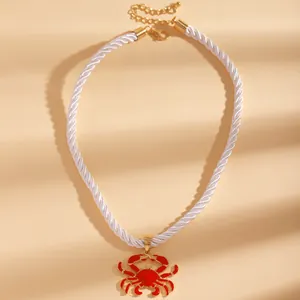 Detailed view of red enamel crab pendant on a white silk twisted cord beach necklace