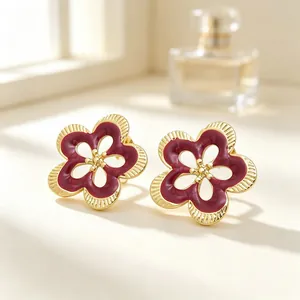 Vista detallada de pendientes de flores vintage con esmalte granate y acabado dorado