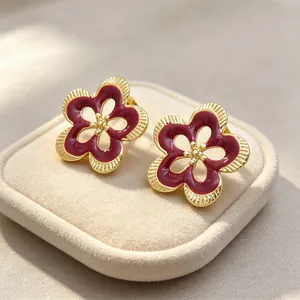 Primer plano de pendientes de flores caladas vintage con esmalte rojo oscuro