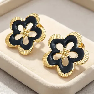 Vista detallada de pendientes de flores huecas en dorado con esmalte negro