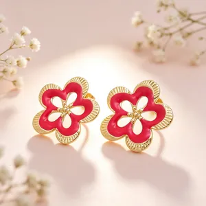 Primer plano de pendientes de flores caladas vintage en esmalte rojo y acero titanio dorado