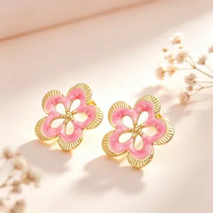 Detalle macro de pendientes de botón de flor de esmalte rosa con acabado dorado pulido
