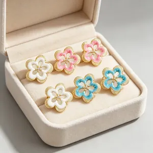 Primer plano de pendientes de flores vintage en esmalte blanco, rosa y azul