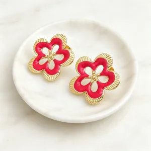 Primer plano detallado de pendientes de flor retro con esmalte rojo y acabado dorado