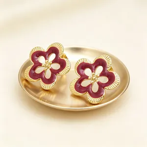 Detalle de pendientes de botón vintage con diseño de flor esmaltada en bandeja dorada