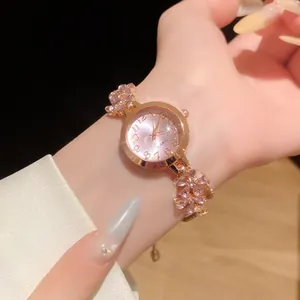 Gros plan d'une montre en or rose avec bracelet fleurs en pierres roses au poignet