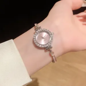 Montre bracelet élégante à cadran rond incrusté de strass sur le poignet d'une femme