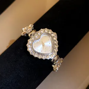 Gros plan d'une montre argentée en forme de cœur avec ornement en strass étincelants