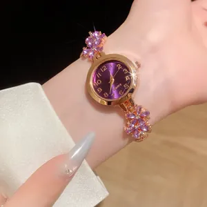 Gros plan d'une montre bracelet dorée élégante avec cadran violet et fleurs en cristal