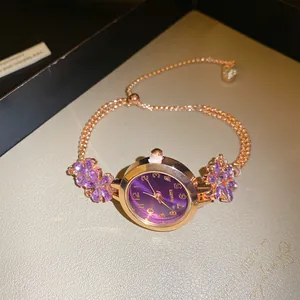 Gros plan détaillé d'une montre bracelet en or rose avec cadran violet et cristaux fleurs.