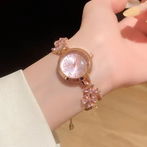 Gros plan d'un élégant bracelet montre en or rose avec des fleurs en cristal rose ajustable.