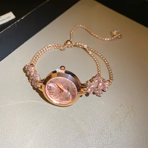 Gros plan d'une montre femme en or rose avec bracelet ajustable orné de fleurs en strass rose