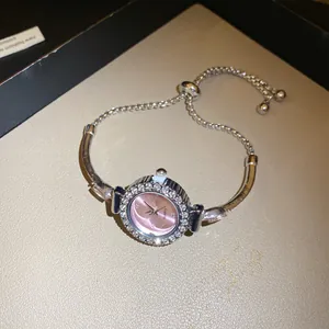 Gros plan d'une montre bracelet à cadran rose avec strass et sa chaîne ajustable