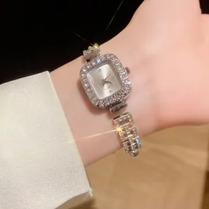 Gros plan d'une montre carrée de luxe élégante avec strass étincelants et bracelet réglable.