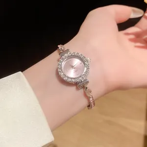 Gros plan d'une montre-bracelet ronde élégante sertie de strass avec un cadran rose pour femme